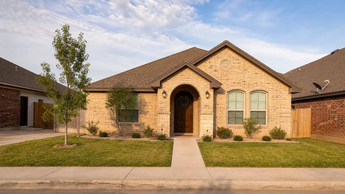 A tidy modest single-family home exterior on a calm Brownsville residential street in warm daylight.