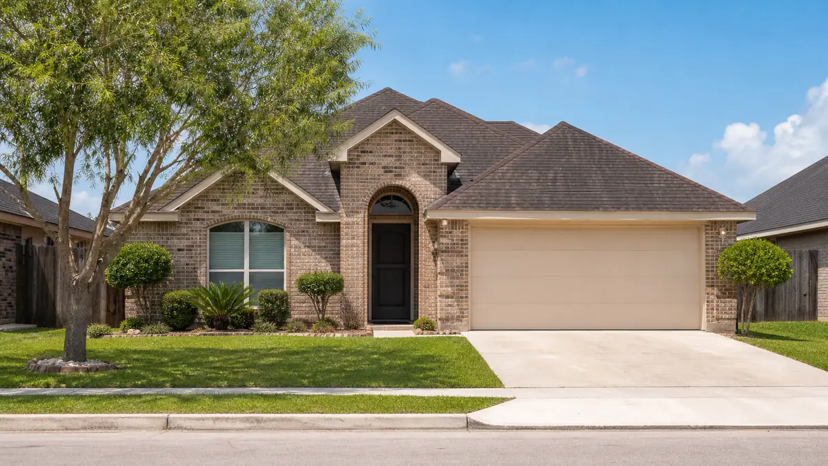 A modest brick single-family home on a sunny Cameron County residential street.