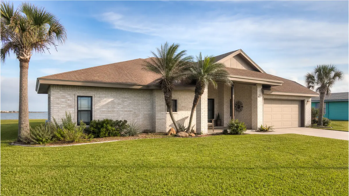 a single-family coastal home with a tidy yard on a breezy Port Isabel street near the water in warm daylight